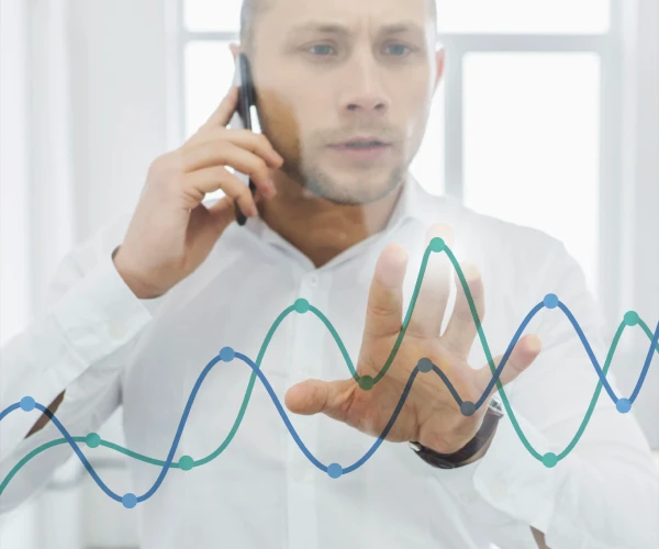 Homem ao telefone analisando linhas de gráficos na tela