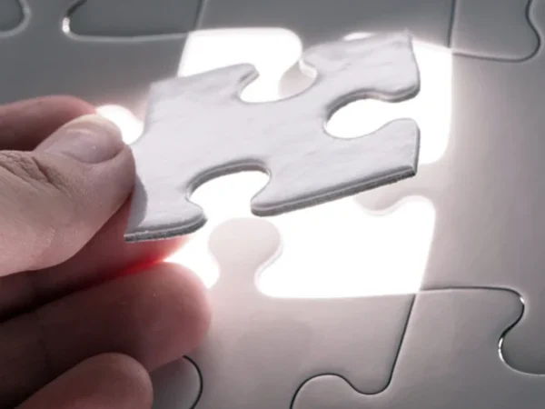 Mão segurando a última peça de um quebra-cabeça