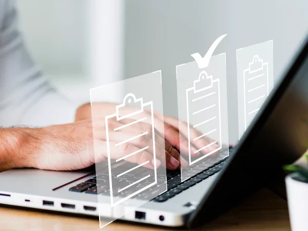 Homem usando um notebook sobre o qual se vê ícones de arquivos, sendo que um deles tem um sinal de "certo"