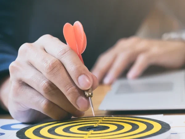 Mão colocando um dardo sobre um alvo