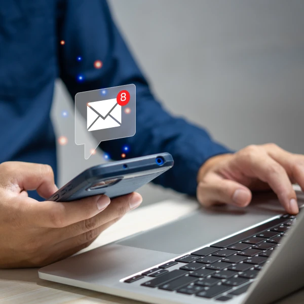 Homem usando um notebook e com um celular na mão direita